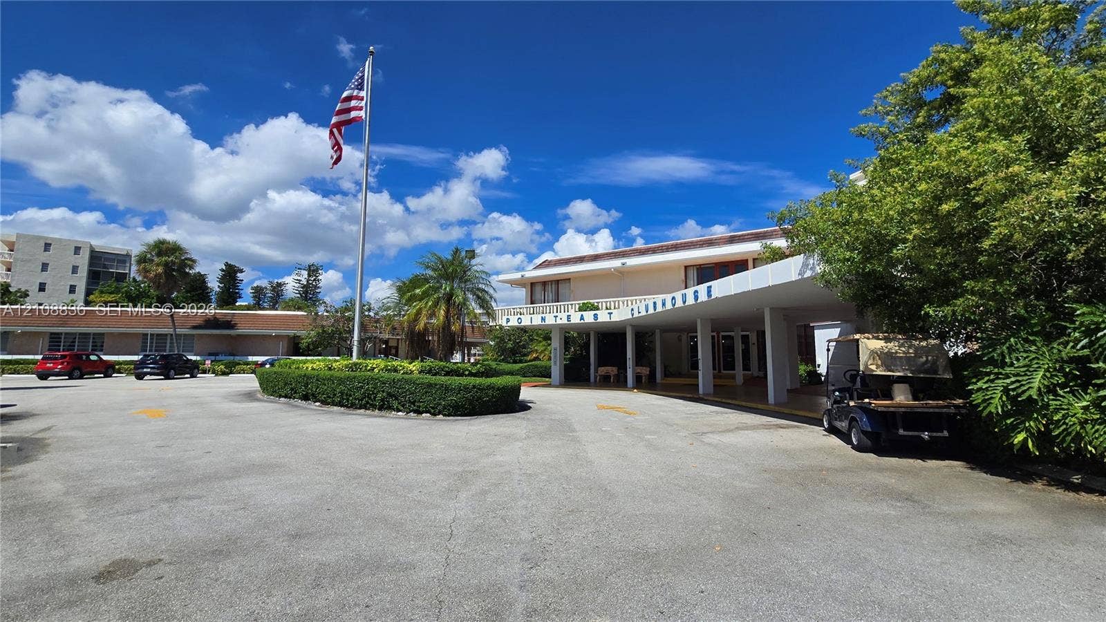 3000 Marcos Drive, #P304, Aventura, FL 33160 Clubhouse exterior featuring a covered porte-cochre, paved parking area, and mature landscaping