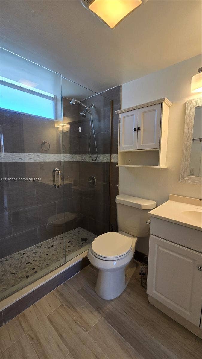 3000 Marcos Drive, #P304, Aventura, FL 33160 Walk-in shower featuring a glass enclosure, stone-tiled floor, and decorative mosaic accent band