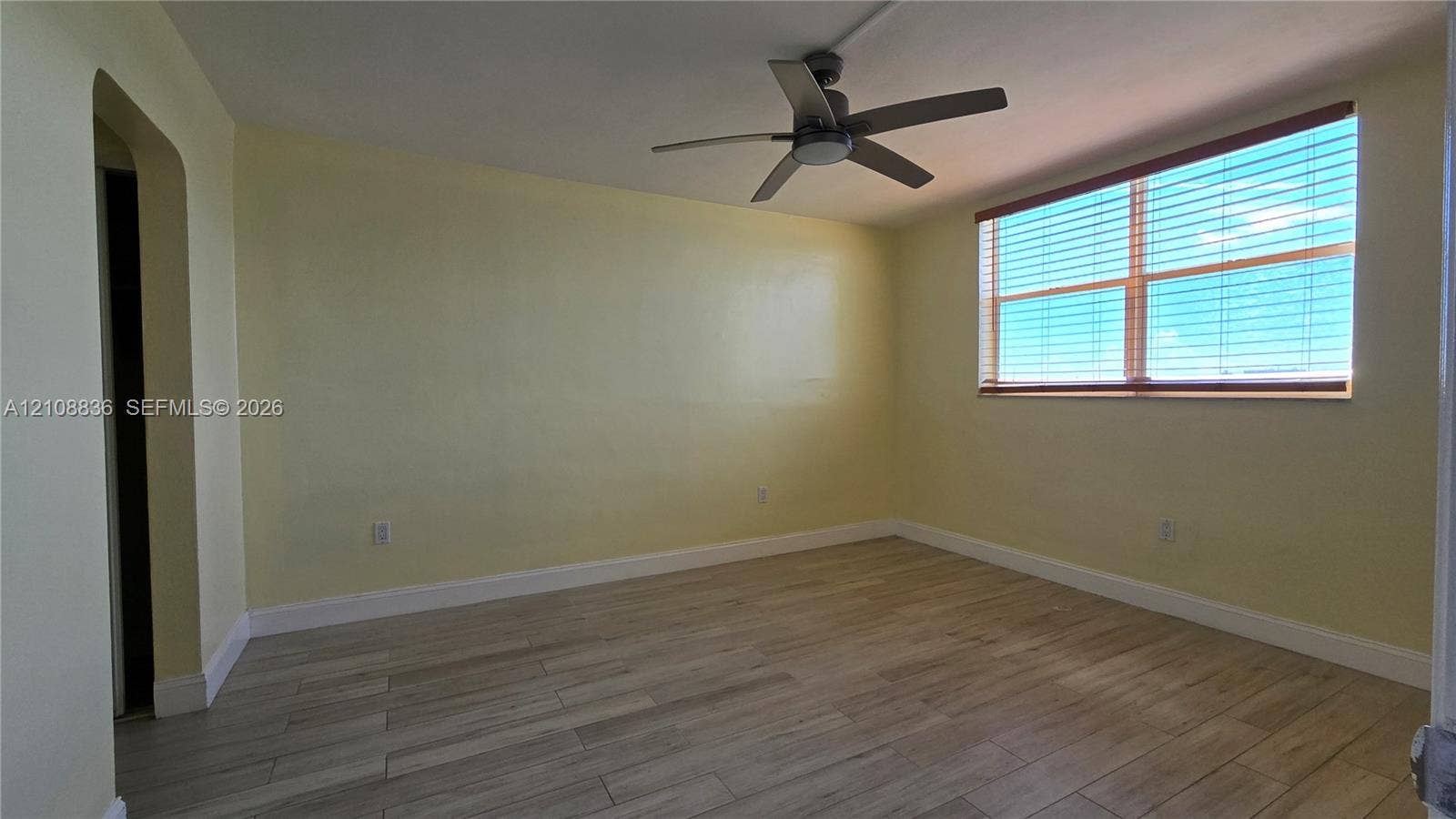 3000 Marcos Drive, #P304, Aventura, FL 33160 Interior room featuring wood-finish tile flooring, a neutral-toned wall finish, a multi-blade ceiling fan, and a large horizontal window with slatted blinds