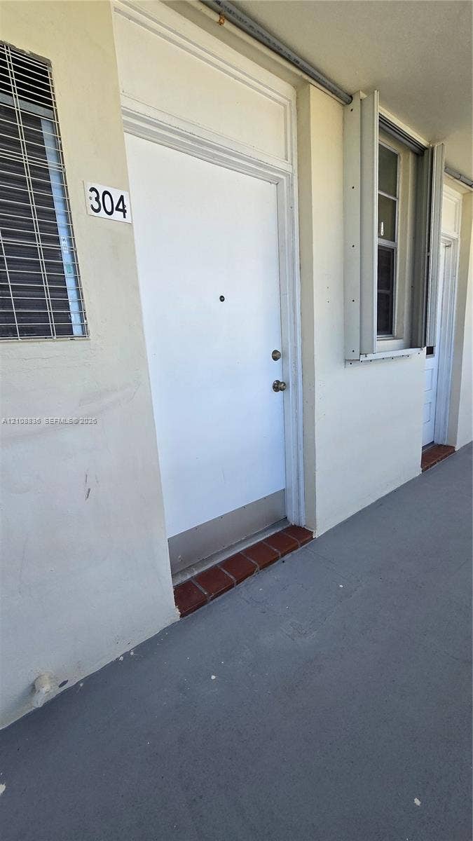 3000 Marcos Drive, #P304, Aventura, FL 33160 Exterior entry featuring a solid white door with a metal kickplate, transom window, and a red brick threshold