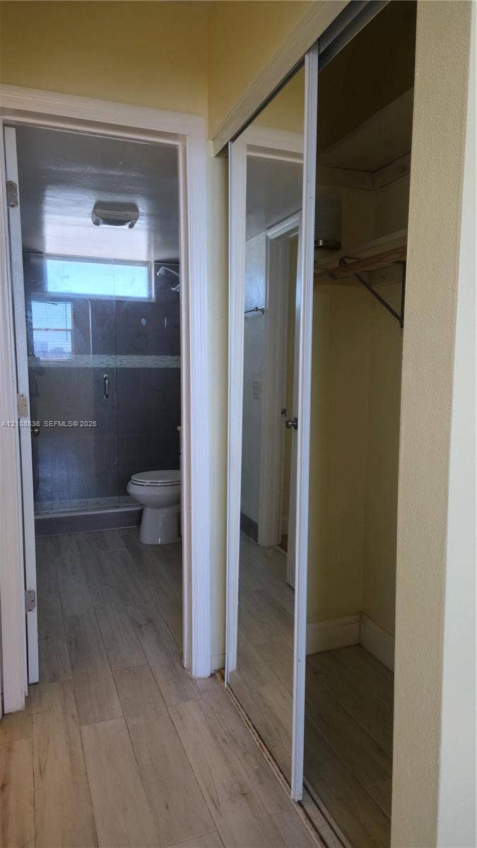 3000 Marcos Drive, #P304, Aventura, FL 33160 Sliding mirrored closet doors, wood-finish flooring, and a walk-in shower with a glass enclosure