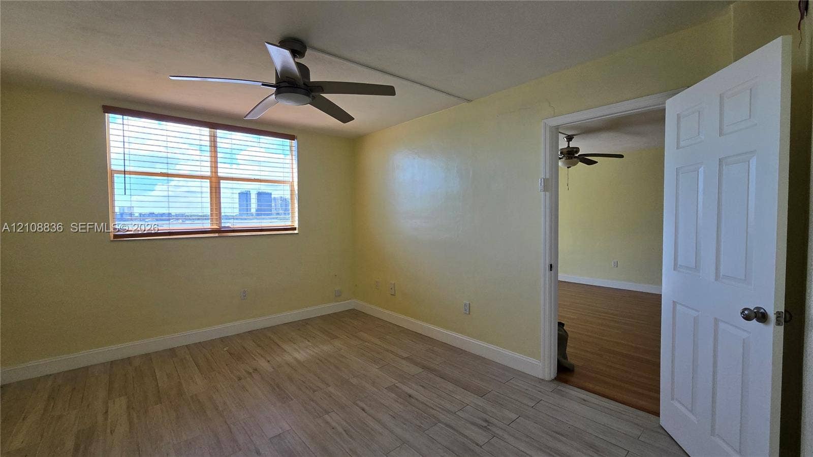 3000 Marcos Drive, #P304, Aventura, FL 33160 Room featuring light-toned wood-finish flooring, a multi-blade ceiling fan, and large horizontal window with slatted blinds