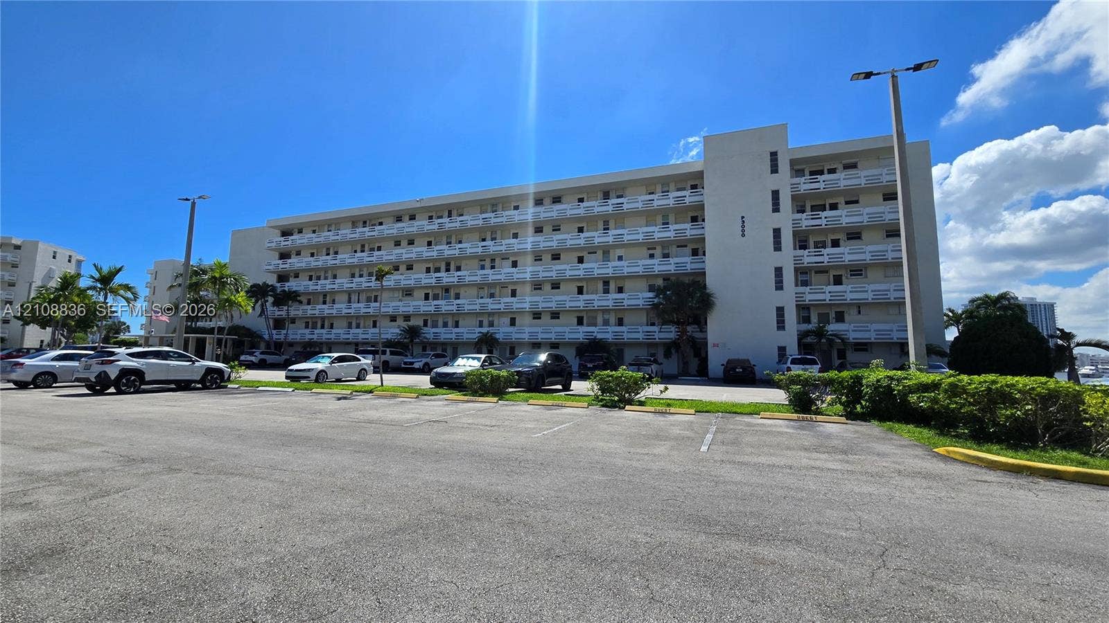 3000 Marcos Drive, #P304, Aventura, FL 33160 Mid-rise concrete exterior featuring uniform balcony railings and paved surface parking