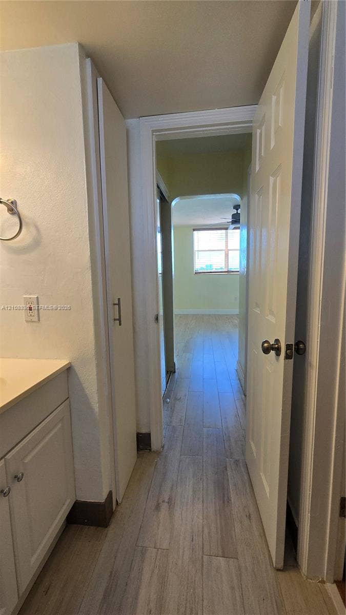 3000 Marcos Drive, #P304, Aventura, FL 33160 Bathroom featuring a vanity with a countertop, integrated floor-to-ceiling cabinetry, and light-toned wood-finish flooring extending into the hallway