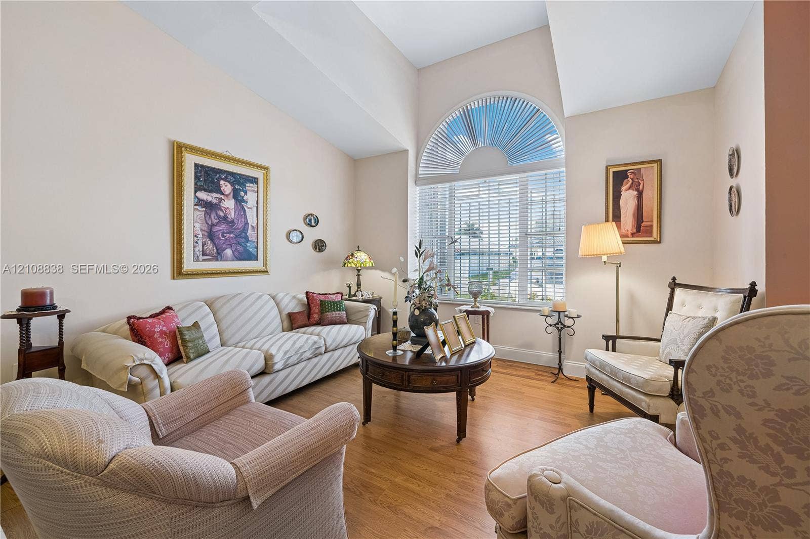 Vaulted ceilings featuring an arched window with louvered blinds and wood-finish flooring