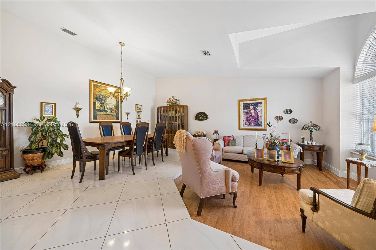 Open-concept area featuring high vaulted ceilings, large-format tile flooring, wood-finish flooring, and arched windows