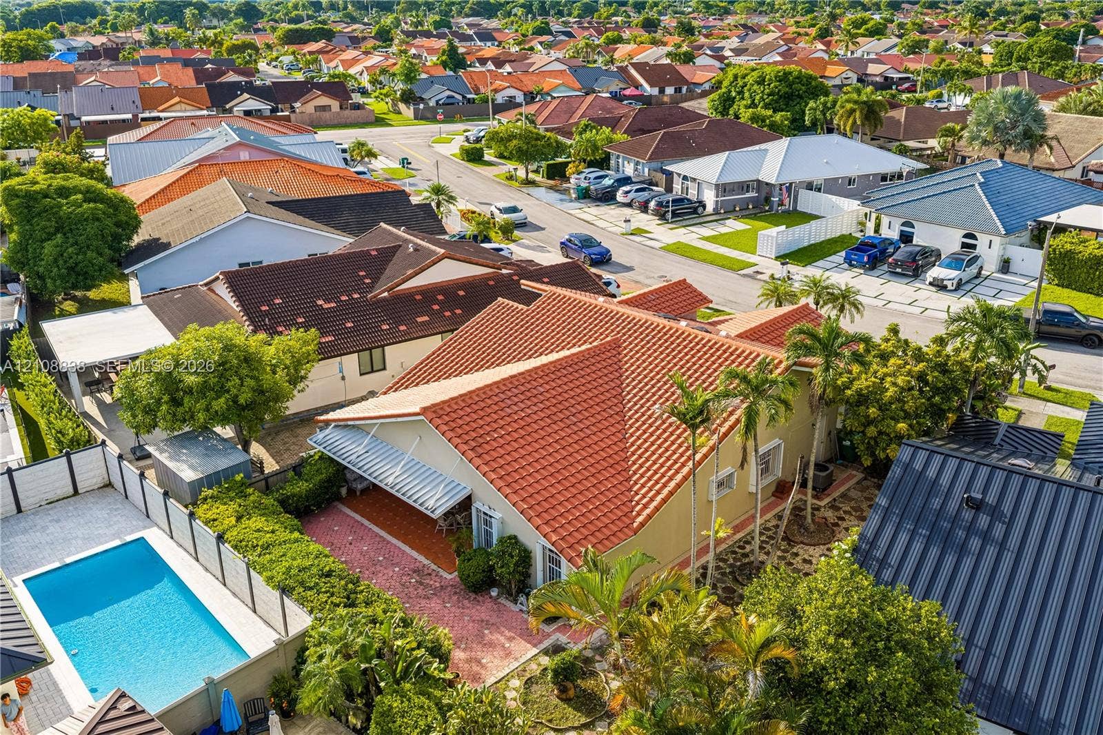 Residential property featuring a terracotta-tiled roof, covered rear patio, private swimming pool, and established landscaping