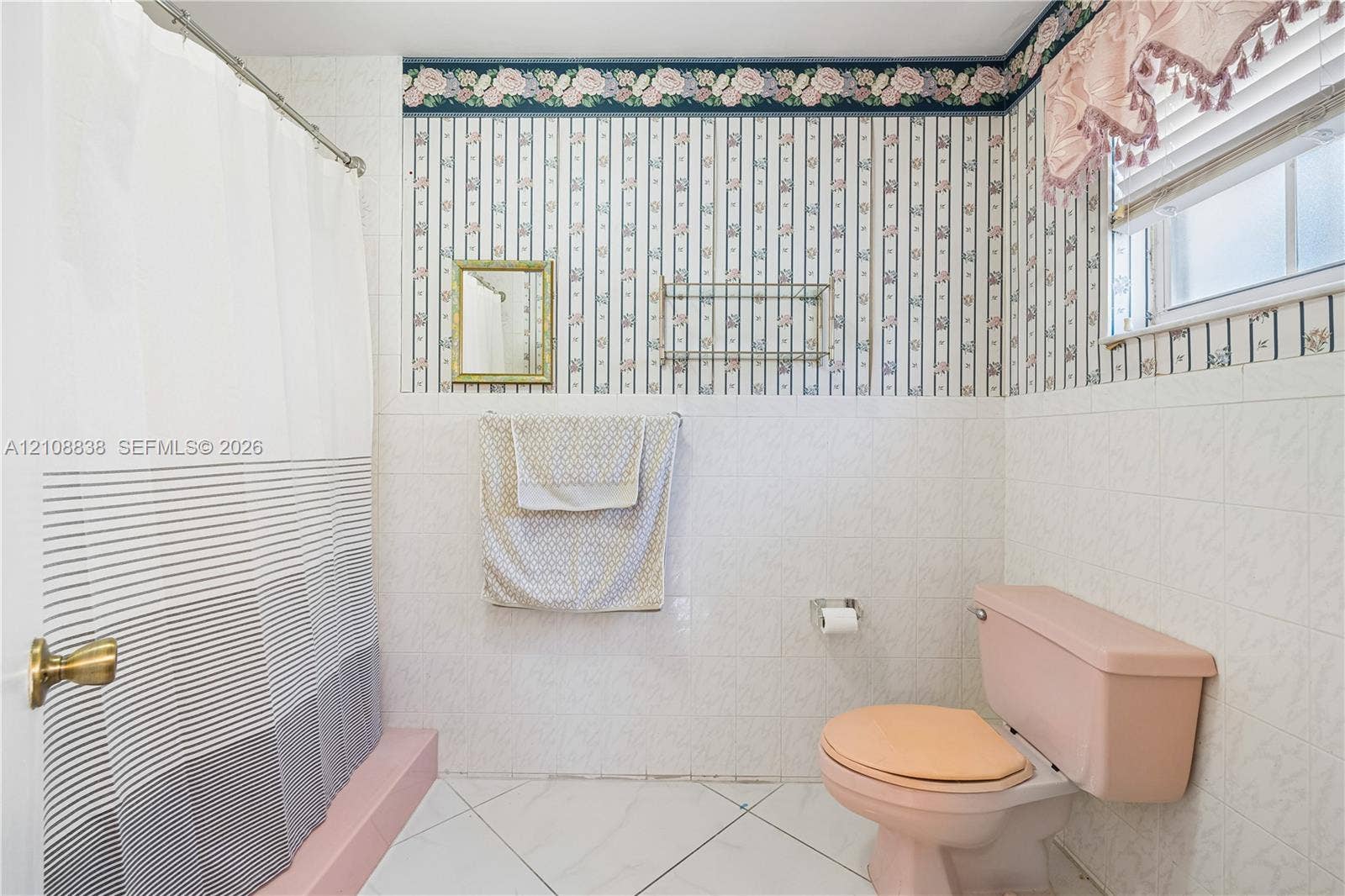 Bathroom featuring white tile wall cladding, patterned wallpaper, a built-in wall-mounted glass shelf, and a shower area with a raised platform