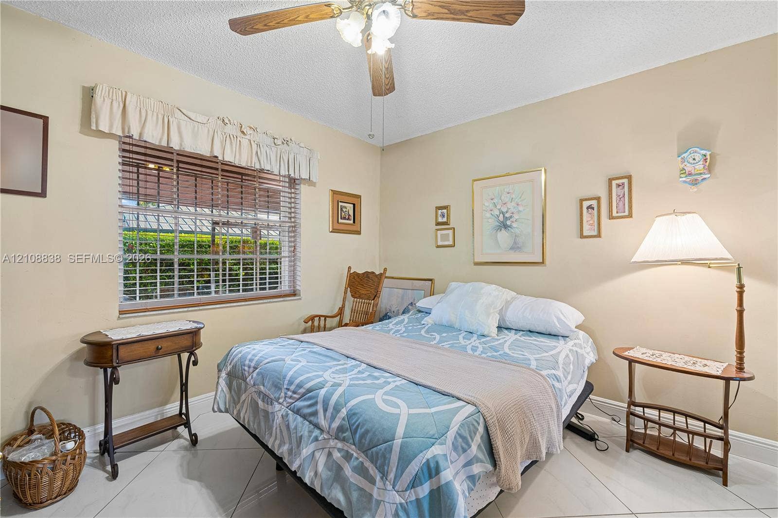 Neutral-toned room featuring large-format tile flooring, a horizontal window with wooden blinds, and a central ceiling fan with an integrated light fixture