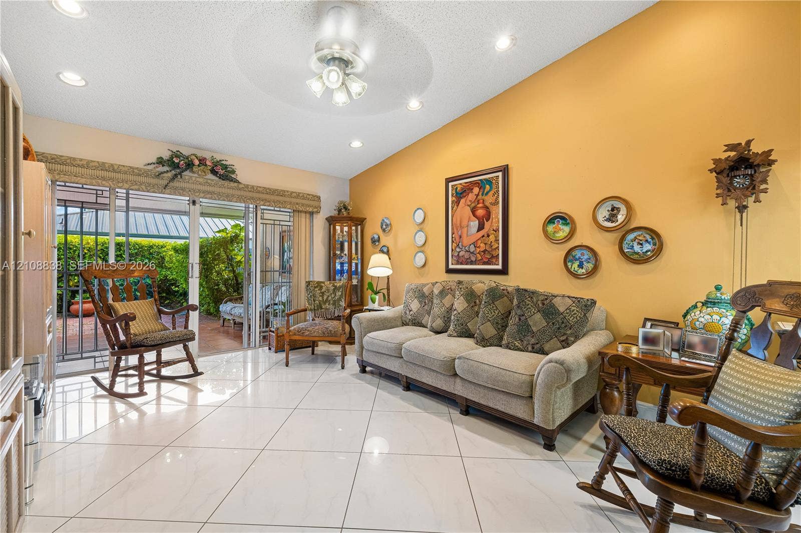 Vaulted ceilings, large-format tile flooring, recessed lighting, ceiling fan with integrated lighting, and sliding glass doors leading to a covered patio