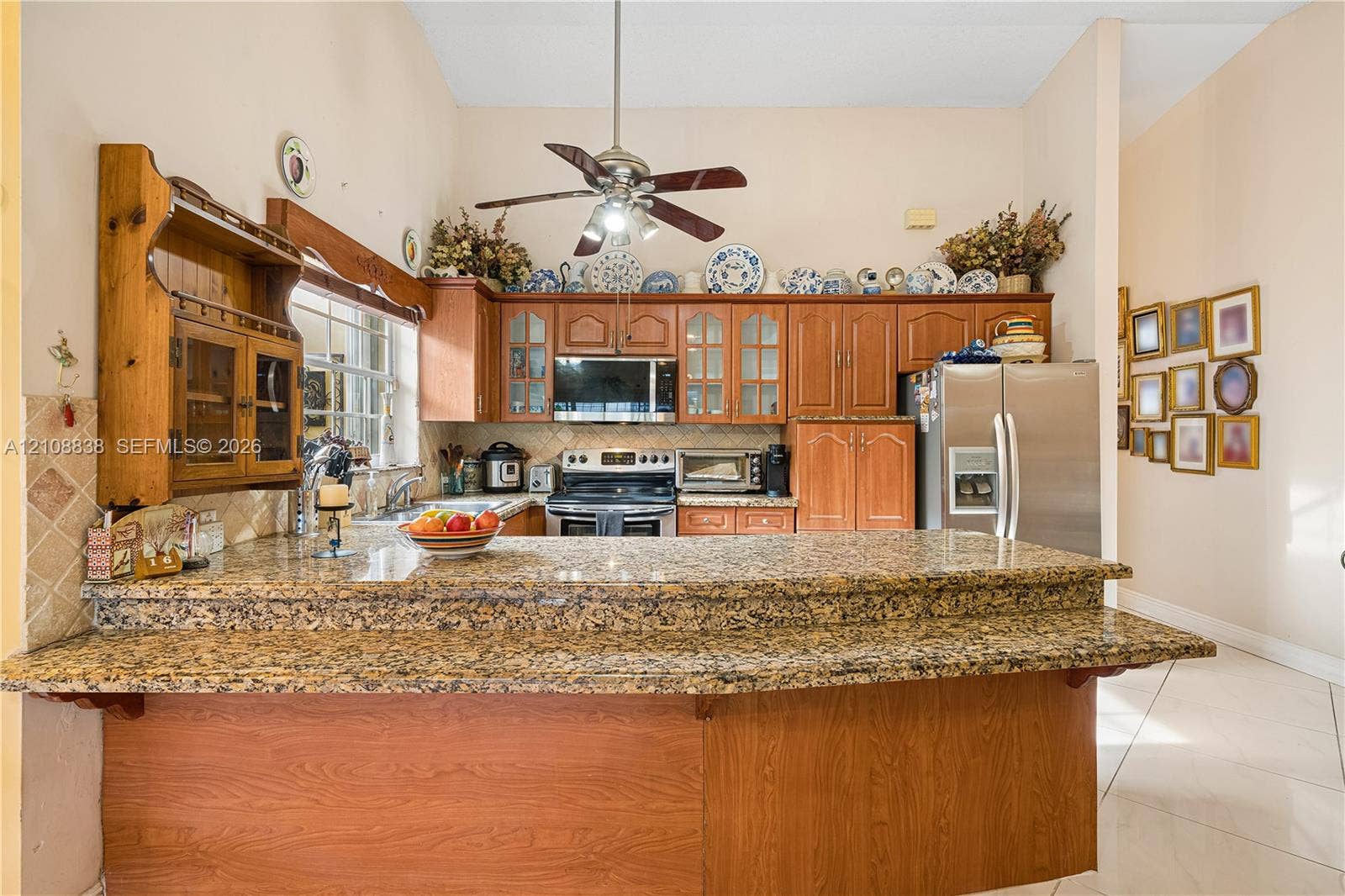 Kitchen featuring raised-panel wood cabinetry, stone countertops, stainless steel appliances, a high ceiling, and tile flooring