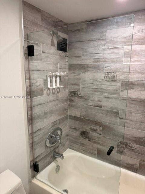Full-height tub enclosure featuring wood-finish tile surround, frameless glass panel, and polished chrome fixtures