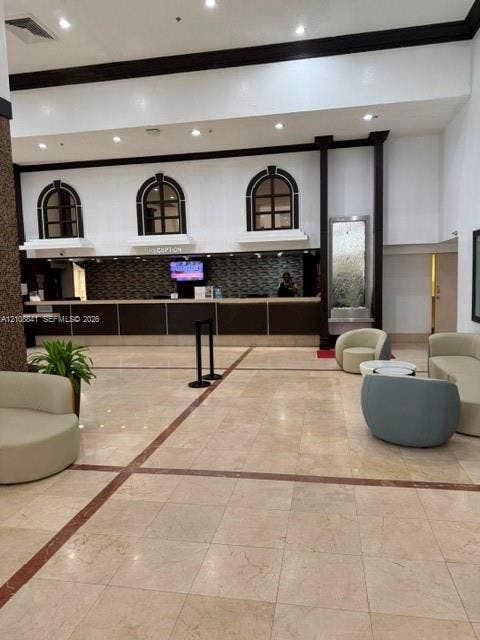 Lobby featuring stone tile flooring, an elongated service counter with a mosaic tile backsplash, built-in recessed arch windows, and an integrated wall-mounted water feature