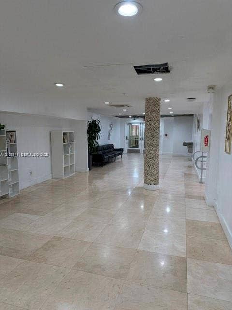 Open-concept interior featuring large-format tile flooring, recessed ceiling lighting, and a decorative textured support column