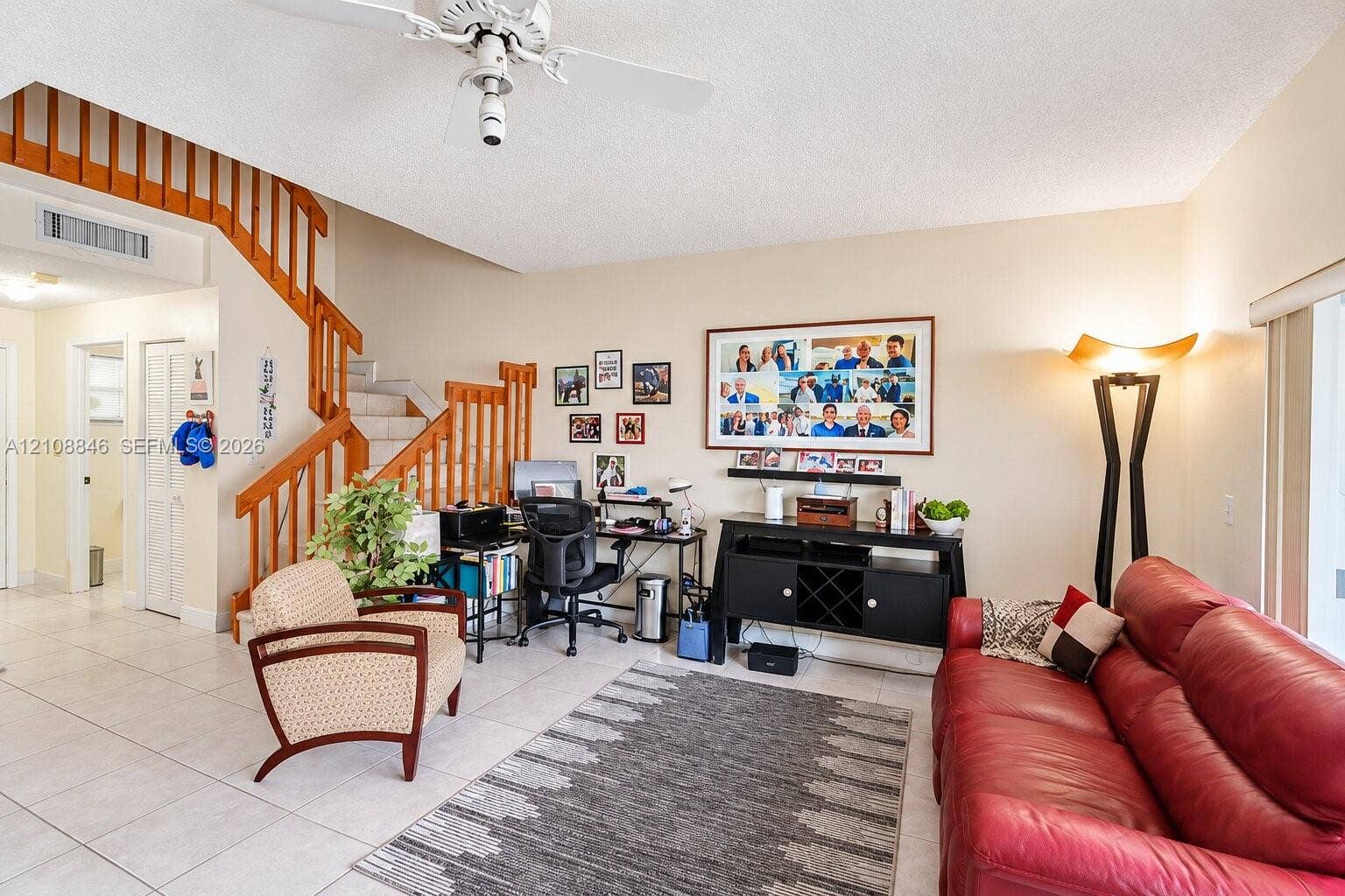 11827 SW 99th Lane, Miami, FL 33186 High-ceiling living area featuring tile flooring, a prominent staircase with wood railings, and a ceiling fan