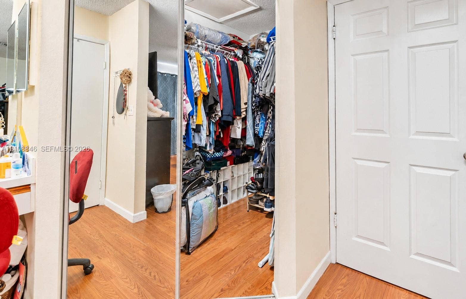 11827 SW 99th Lane, Miami, FL 33186 Walk-in closet featuring mirrored sliding doors, wood-finish flooring, and white paneled interior doors