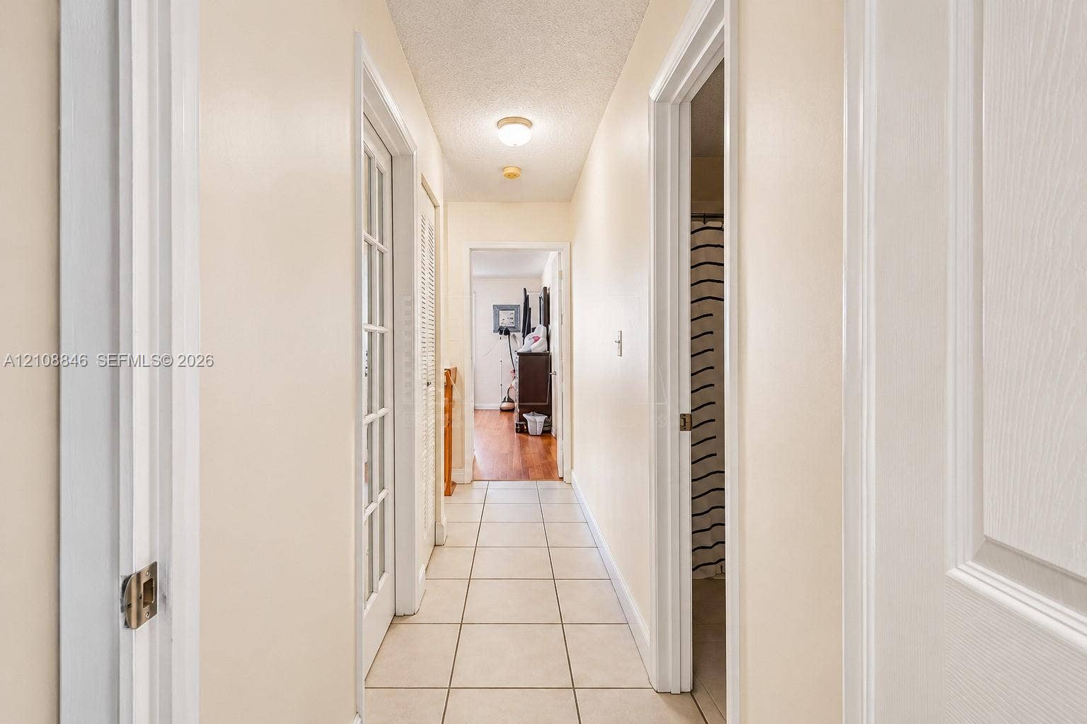 11827 SW 99th Lane, Miami, FL 33186 Hallway featuring ceramic tile flooring, a multi-pane glass door, louvered closet doors, and a flush-mount ceiling light fixture