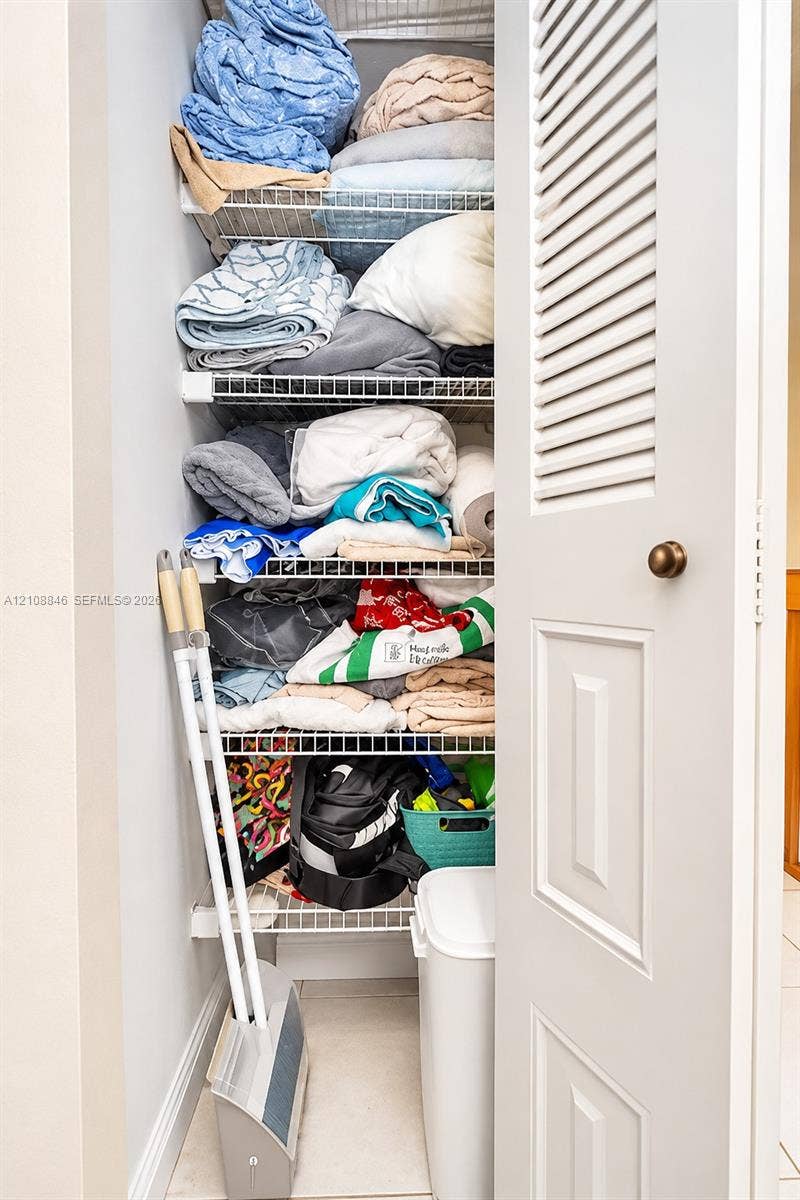 11827 SW 99th Lane, Miami, FL 33186 Storage closet featuring white louvered door, brass-finish hardware, and multiple levels of white coated wire shelving