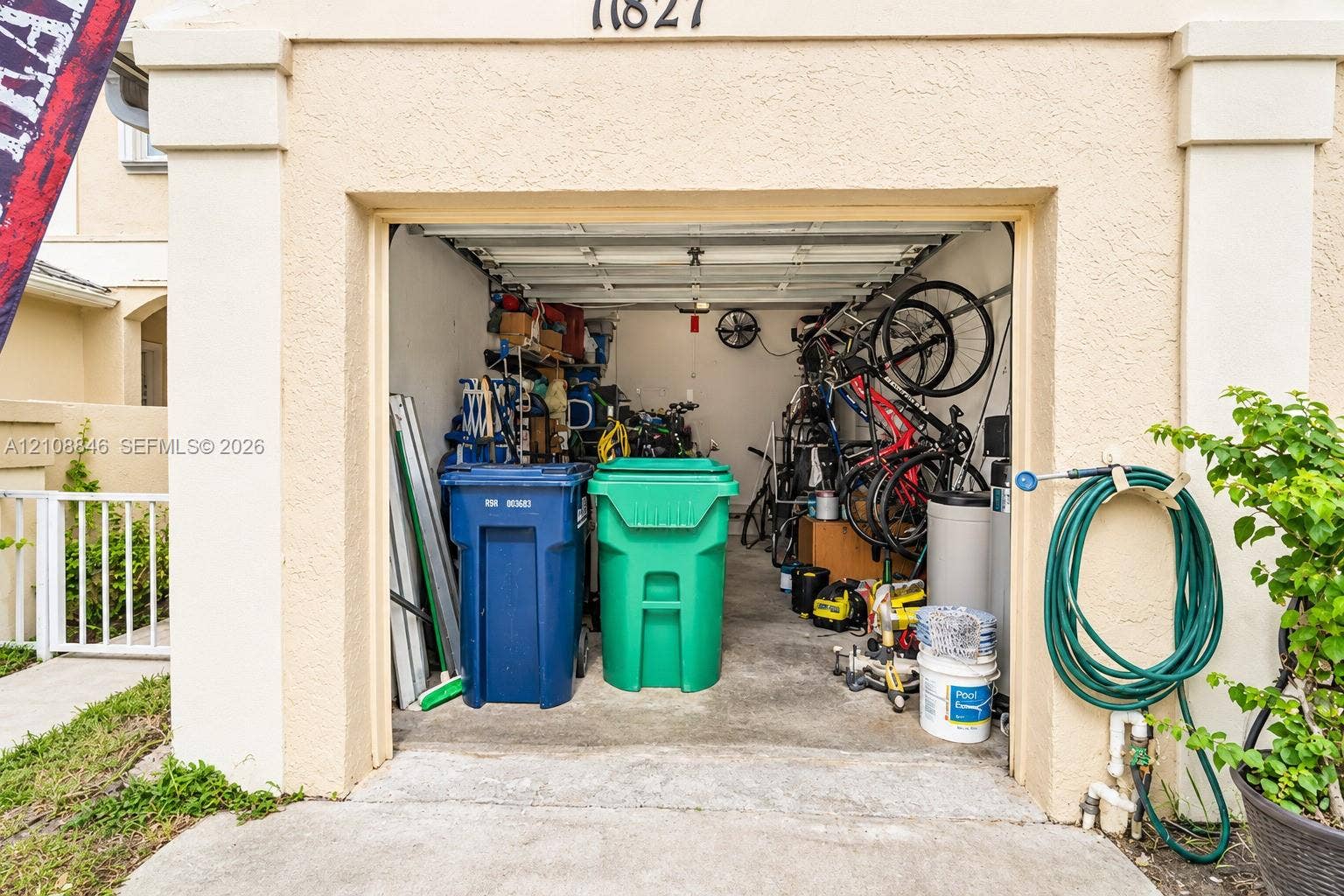 11827 SW 99th Lane, Miami, FL 33186 Single-car garage featuring a concrete floor, ceiling-mounted hardware, and exterior spigot