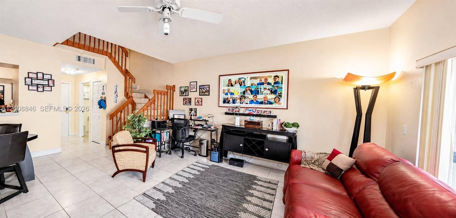 11827 SW 99th Lane, Miami, FL 33186 Open-concept main living area featuring light-toned tile flooring, wood-spindle staircase, and sliding glass door