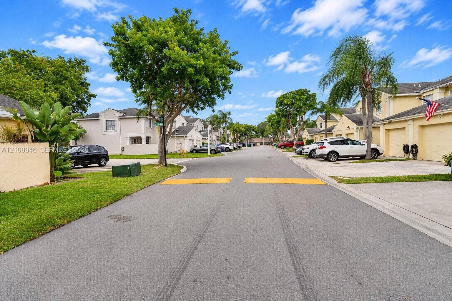 11827 SW 99th Lane, Miami, FL 33186 Multi-family residential community featuring stucco exterior finishes, concrete driveways, attached garages, paved streets, and mature landscaping
