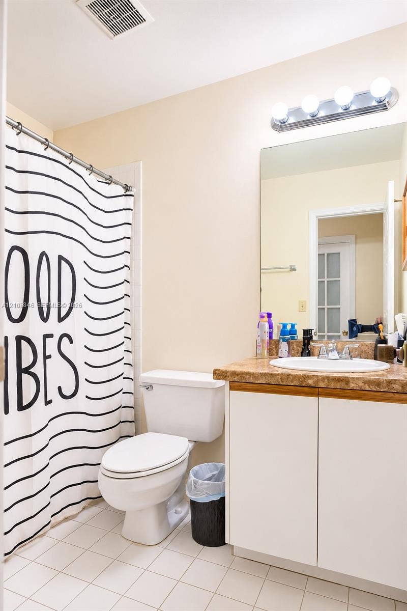 11827 SW 99th Lane, Miami, FL 33186 Bathroom featuring a vanity with a stone-finish countertop, integrated sink, white cabinetry, wall-mounted four-bulb lighting fixture, and tile flooring