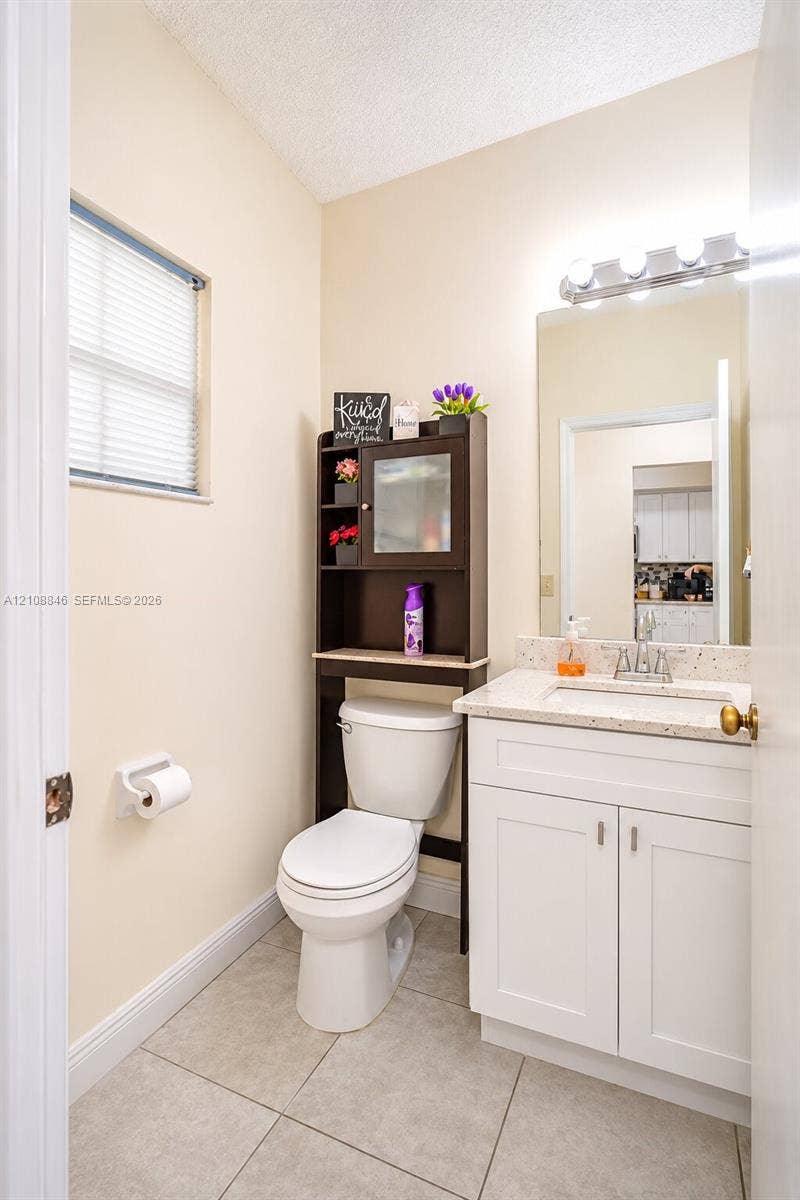 11827 SW 99th Lane, Miami, FL 33186 White vanity with stone-composite countertop, undermount sink, ceramic tile flooring, and integrated wall mirror with overhead light fixture