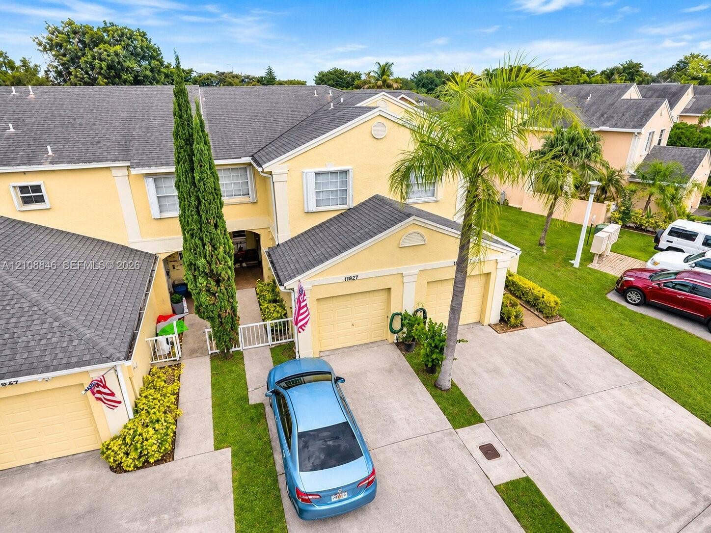 11827 SW 99th Lane, Miami, FL 33186 Two-story residence featuring a multi-gabled roofline, stucco exterior, attached two-car garage, concrete driveway, and established palm landscaping