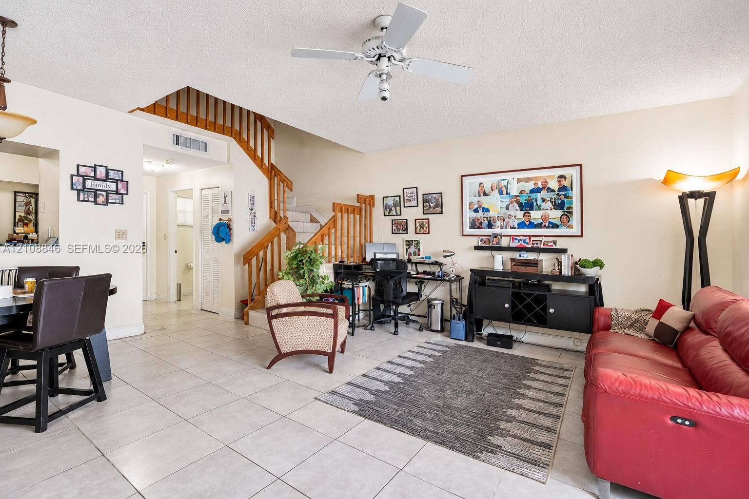 11827 SW 99th Lane, Miami, FL 33186 Open-concept living space featuring ceramic tile flooring, a wooden staircase with vertical balusters, and a ceiling fan