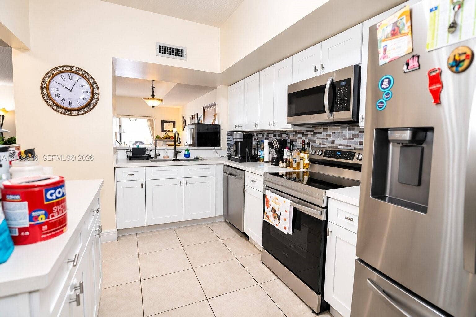 11827 SW 99th Lane, Miami, FL 33186 Kitchen featuring white cabinetry, stainless steel appliances, multi-toned tile backsplash, and light-toned tile flooring