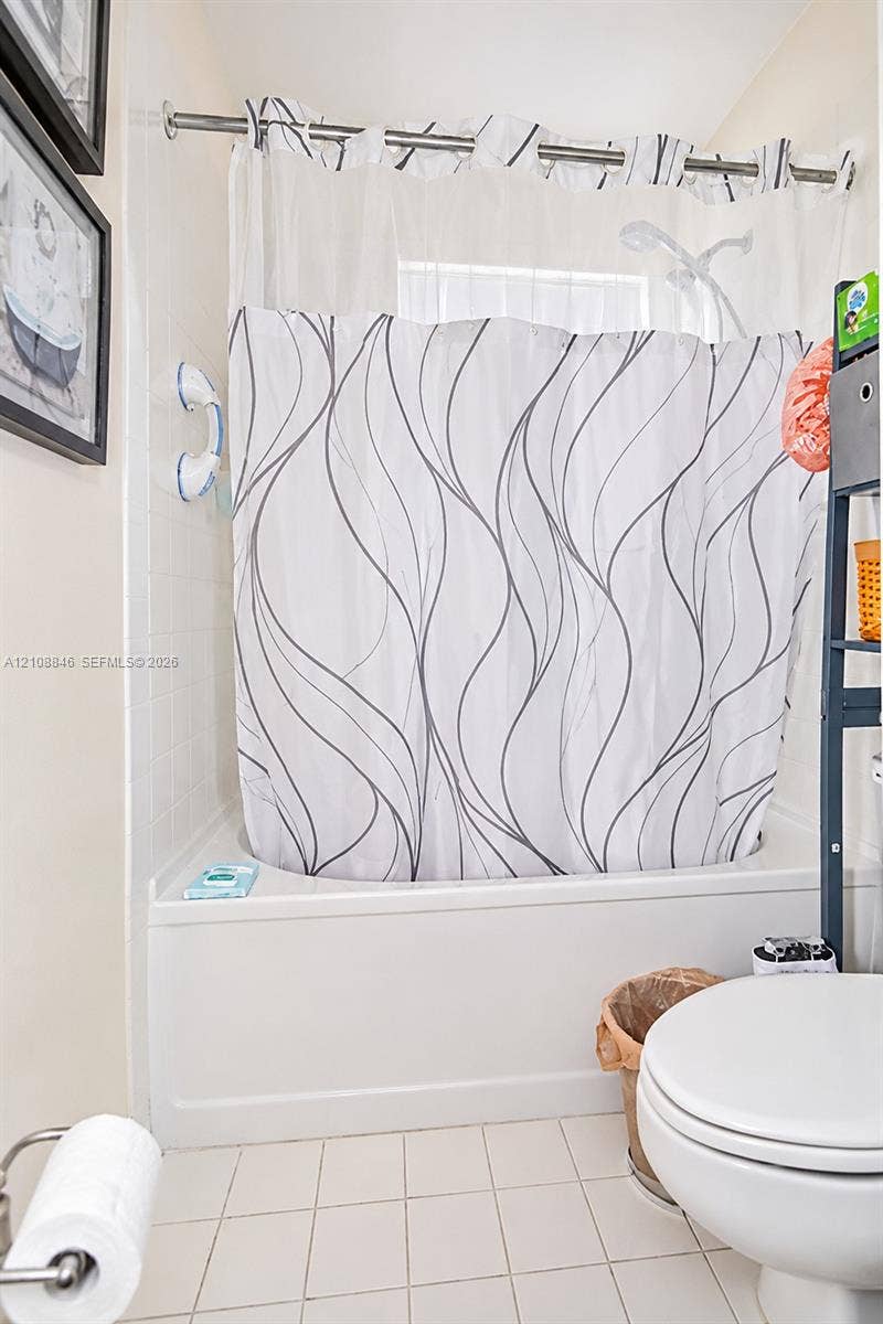 11827 SW 99th Lane, Miami, FL 33186 Tub-shower combination featuring white tile surround, integrated shelving, and metal shower rod hardware