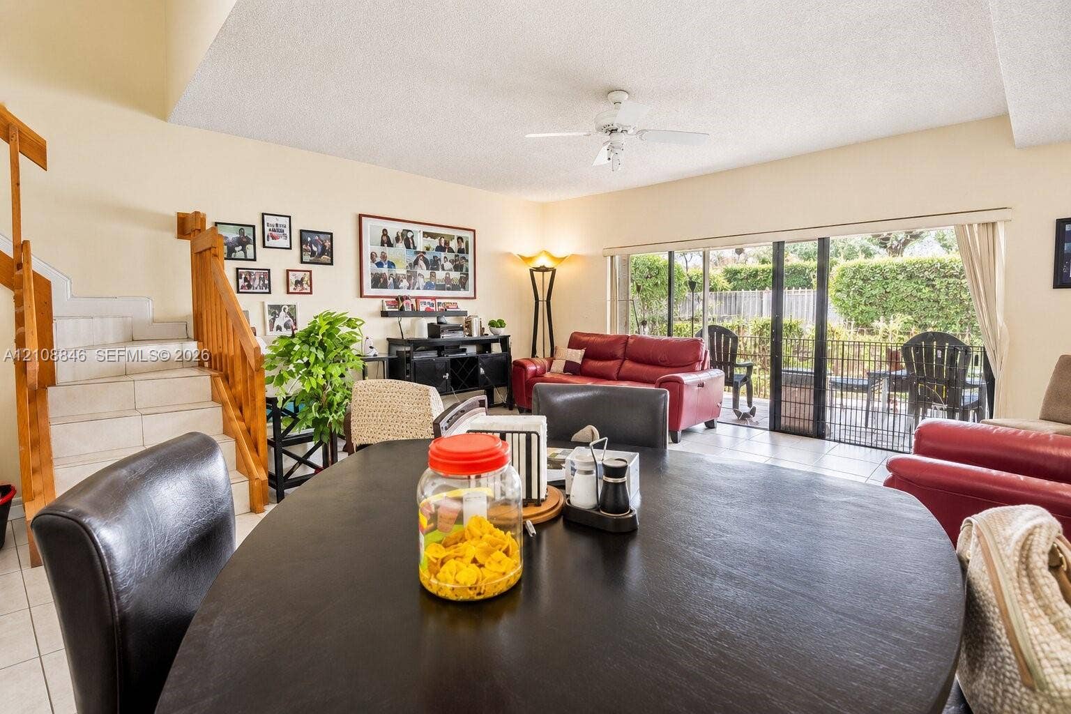11827 SW 99th Lane, Miami, FL 33186 Open-concept interior featuring light-toned tile flooring, a wooden staircase with integrated railing, and expansive glass sliding doors
