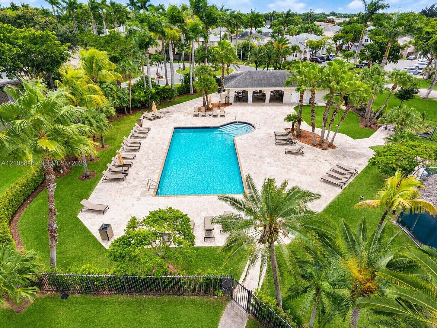 11827 SW 99th Lane, Miami, FL 33186 Community swimming pool featuring a stone-paver deck, integrated step entry, shaded pavilion, and surrounding mature landscaping