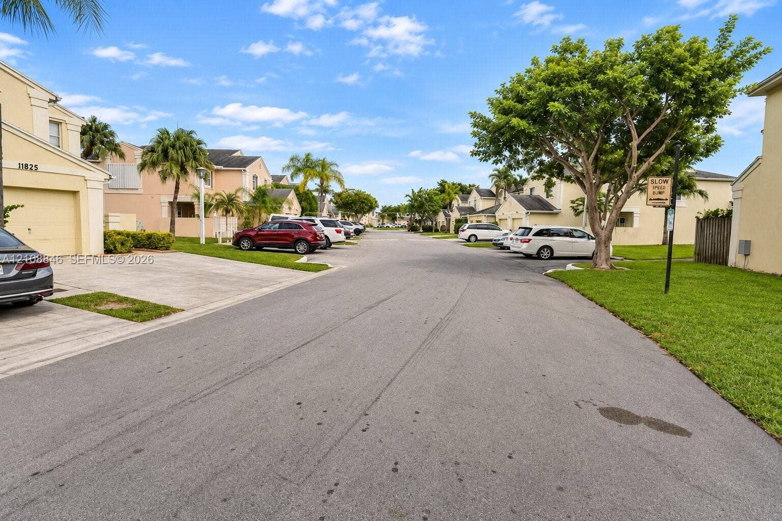 11827 SW 99th Lane, Miami, FL 33186 Residential streetscape featuring stucco-finished exteriors, paved driveways, attached garages, and established landscaping with mature palm and broadleaf trees