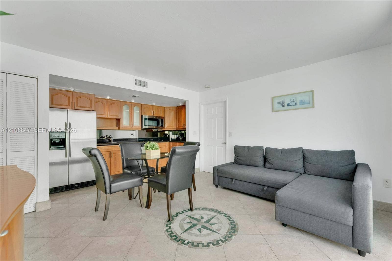Kitchen featuring wood cabinetry, stainless steel refrigerator, and stone-finish countertops, paired with tile flooring throughout