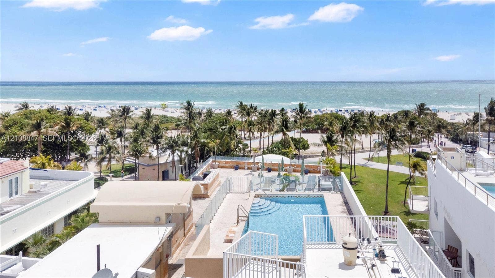 Rooftop swimming pool featuring glass panel perimeter fencing, masonry hardscaping, and an expansive ocean backdrop
