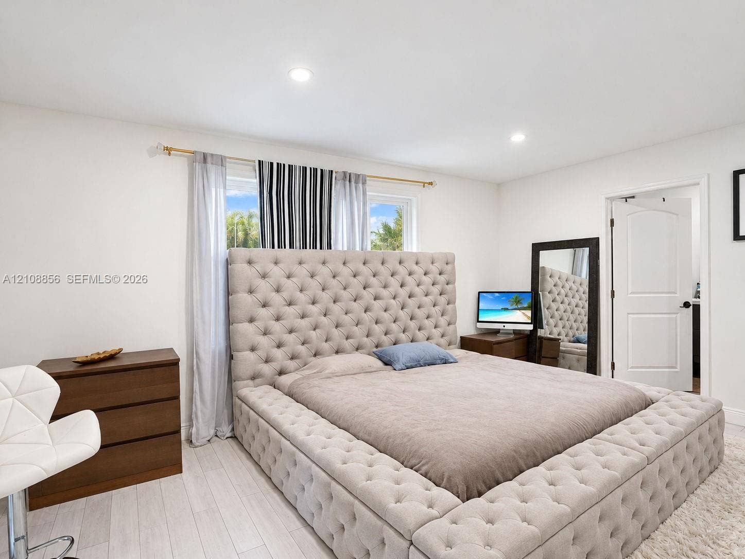 Neutral-toned wood-finish flooring, recessed lighting, and a multi-panel interior door