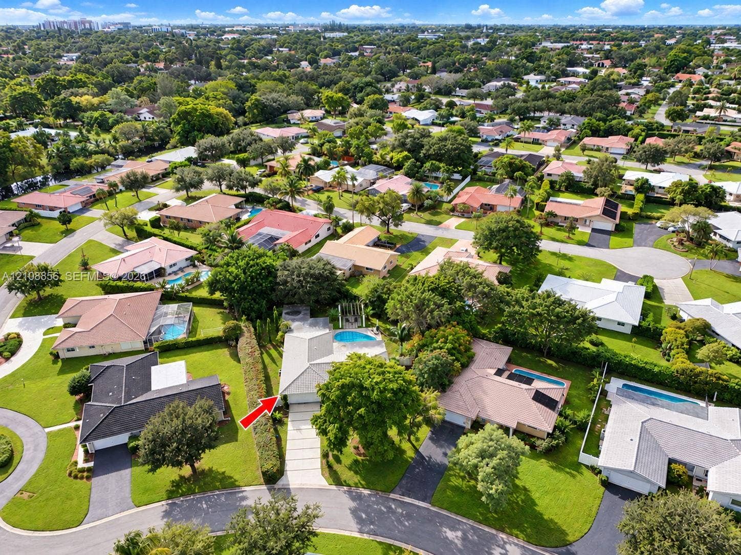 Aerial perspective of property featuring a concrete driveway, multi-paneled roof, and an in-ground swimming pool