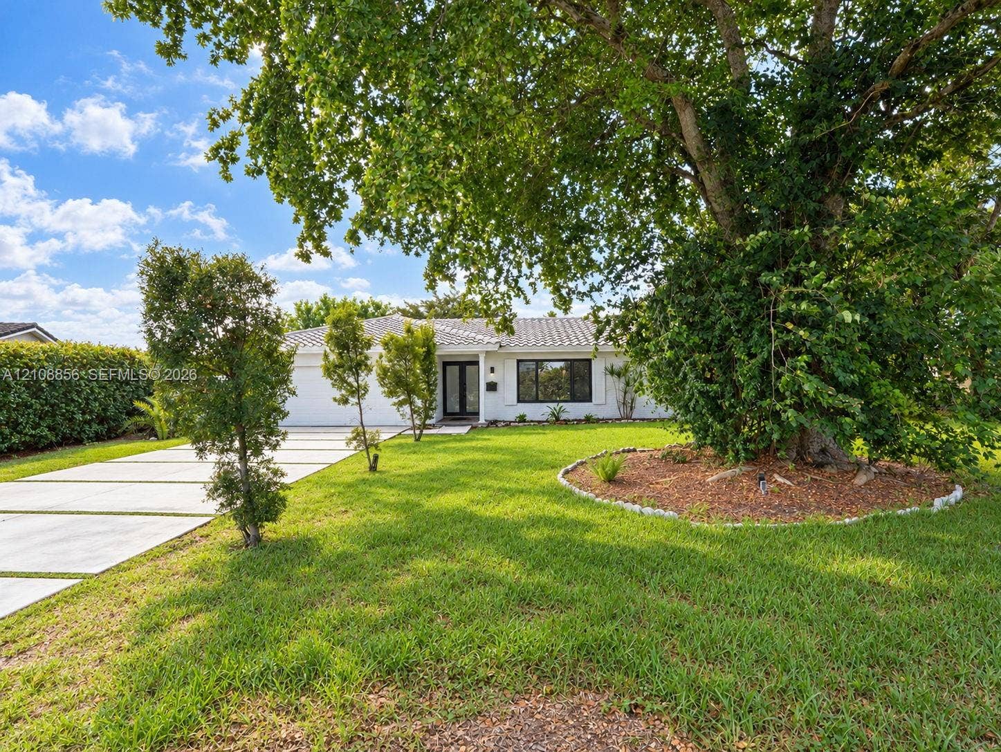 Single-story exterior featuring white stucco siding, a tiled roof, a multi-panel glass entry door, and a concrete driveway