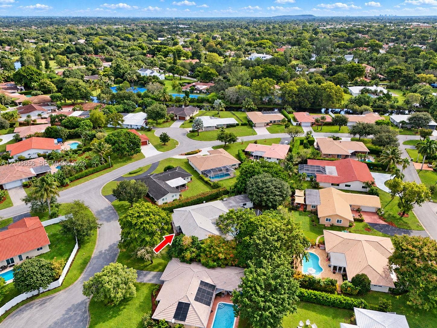 Aerial perspective of a suburban neighborhood featuring tree-lined streets, landscaped lots, and proximity to green space