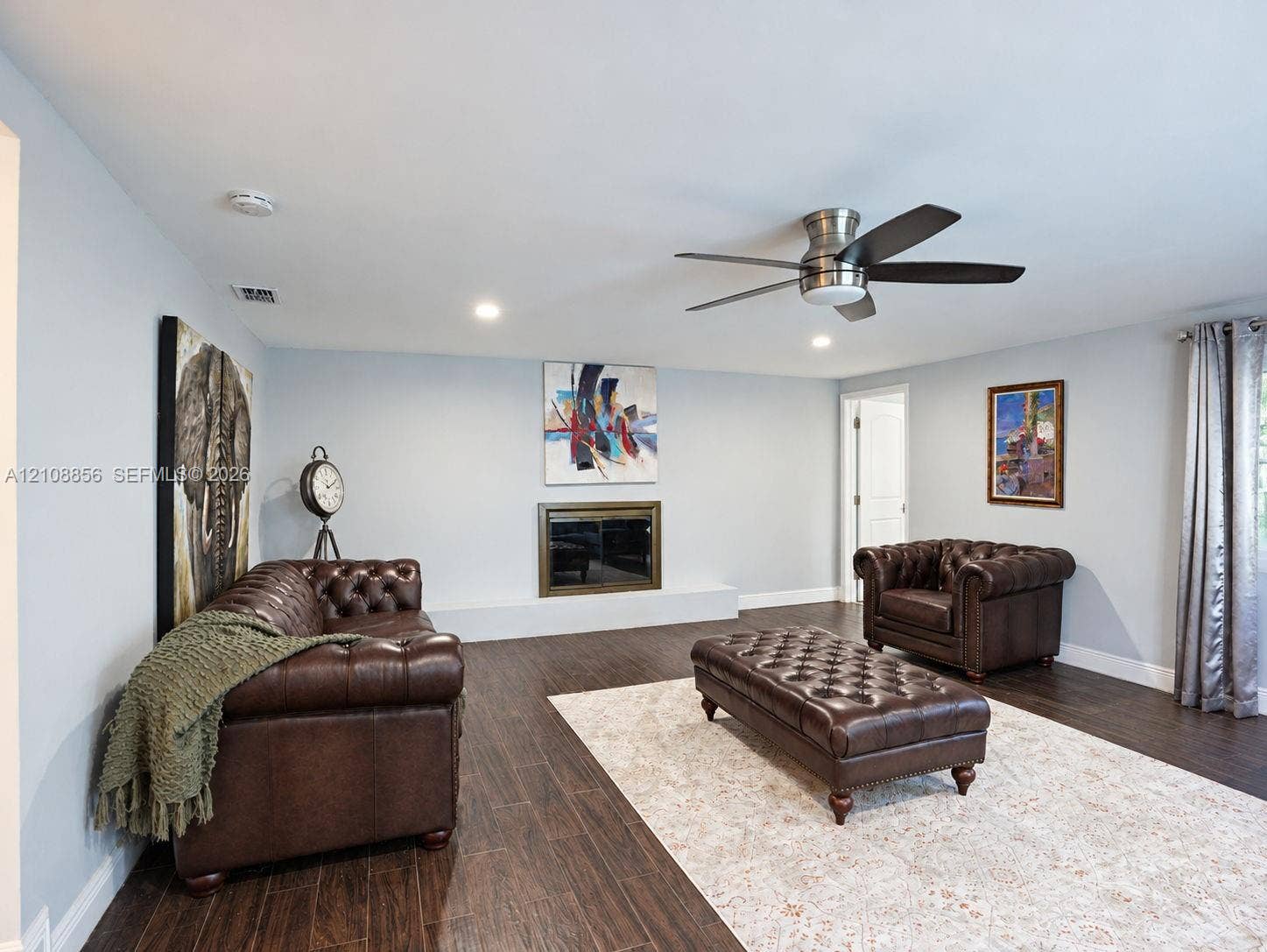 Living space featuring wood-finish flooring, a flush-mounted ceiling fan, recessed lighting, and a fireplace with a metallic surround