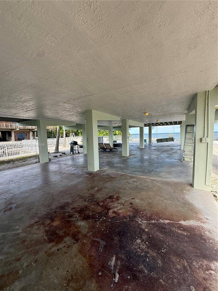 Elevated foundation featuring reinforced concrete structural supports, expansive covered hardscaping, and water frontage