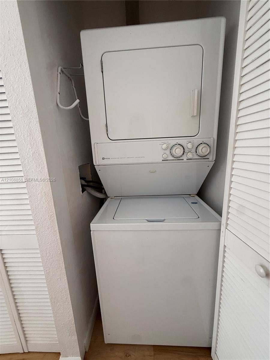 Stacked white washer and dryer unit enclosed by bi-fold louvered doors