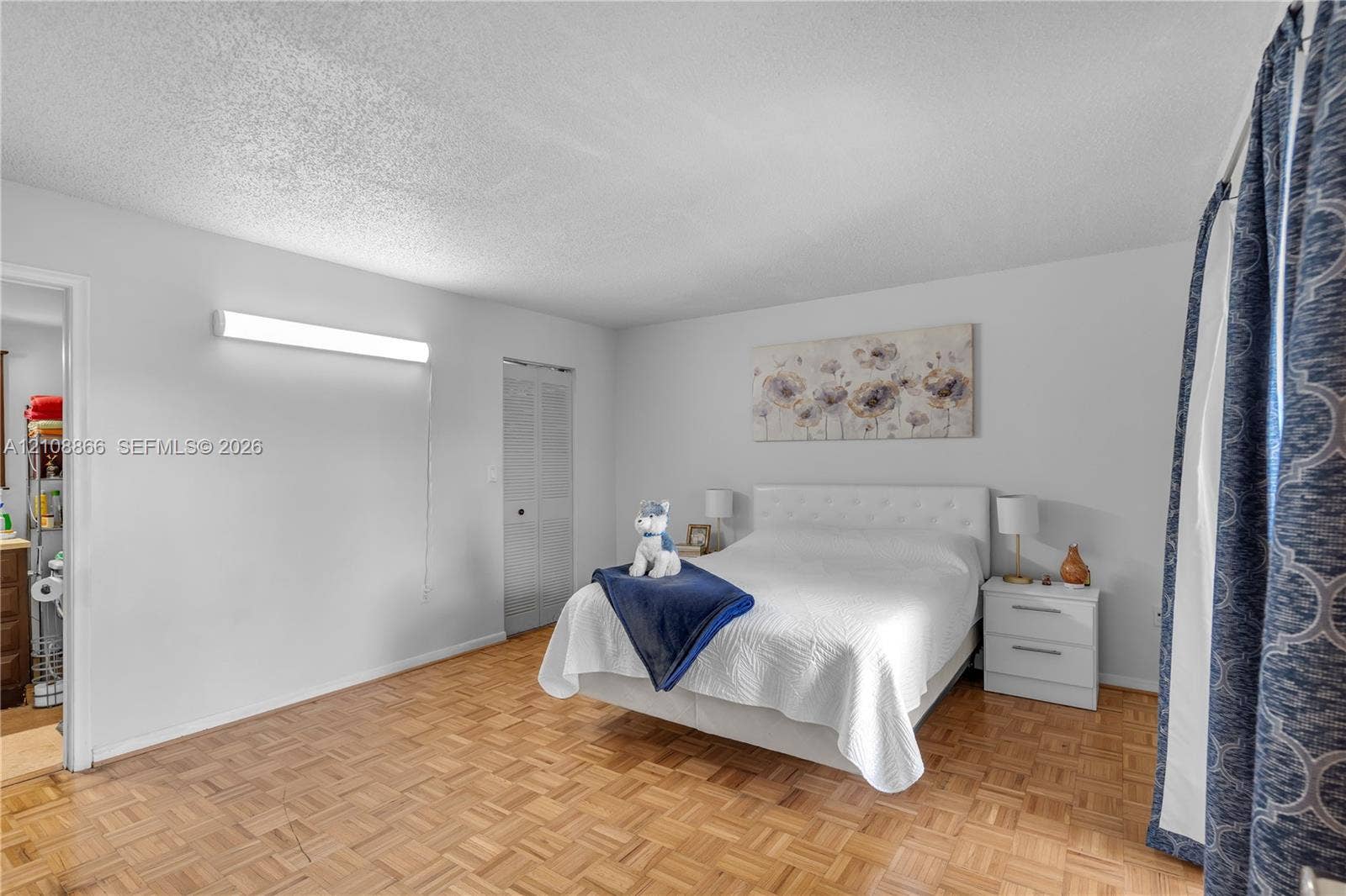 10859 NW 7th Street, #21-18, Miami, FL 33172 Parquet wood-finish flooring, textured ceiling, wall-mounted linear light fixture, and louvered-panel closet doors