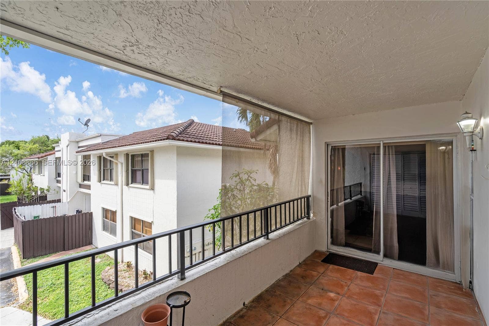 10859 NW 7th Street, #21-18, Miami, FL 33172 Covered balcony featuring terracotta-style tile flooring, metal railing, integrated wall-mounted exterior lighting, and sliding glass entry doors