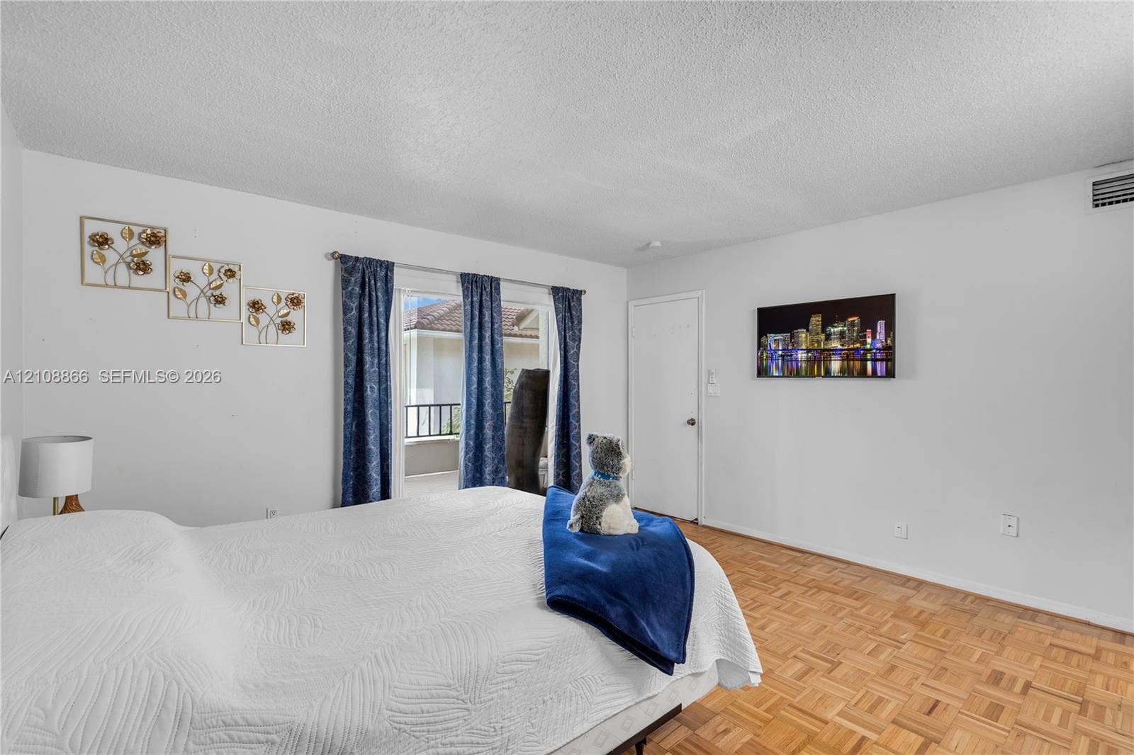 10859 NW 7th Street, #21-18, Miami, FL 33172 Interior space featuring wood-finish parquet flooring, textured ceiling, and a sliding glass door providing external access to a balcony with a railing