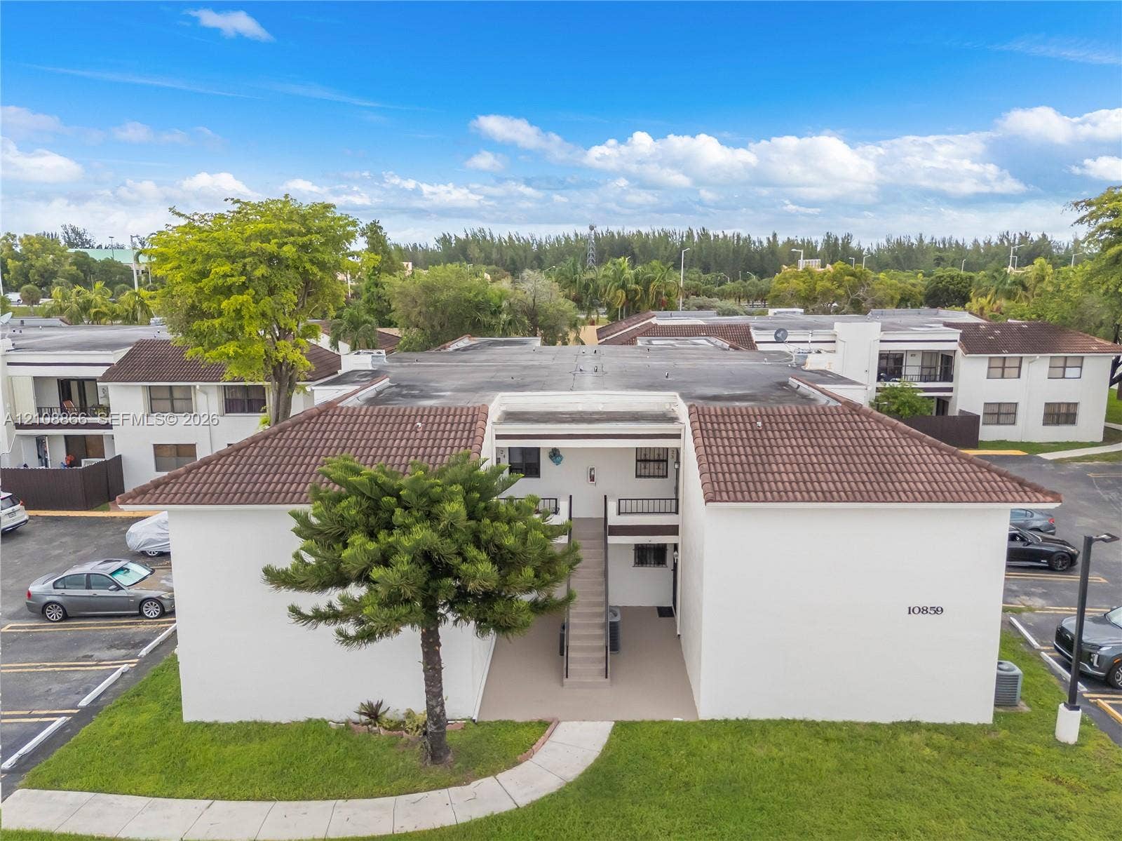 10859 NW 7th Street, #21-18, Miami, FL 33172 Exterior featuring a multi-story stucco facade, a hipped roof with clay tile shingles, and a central open-air staircase