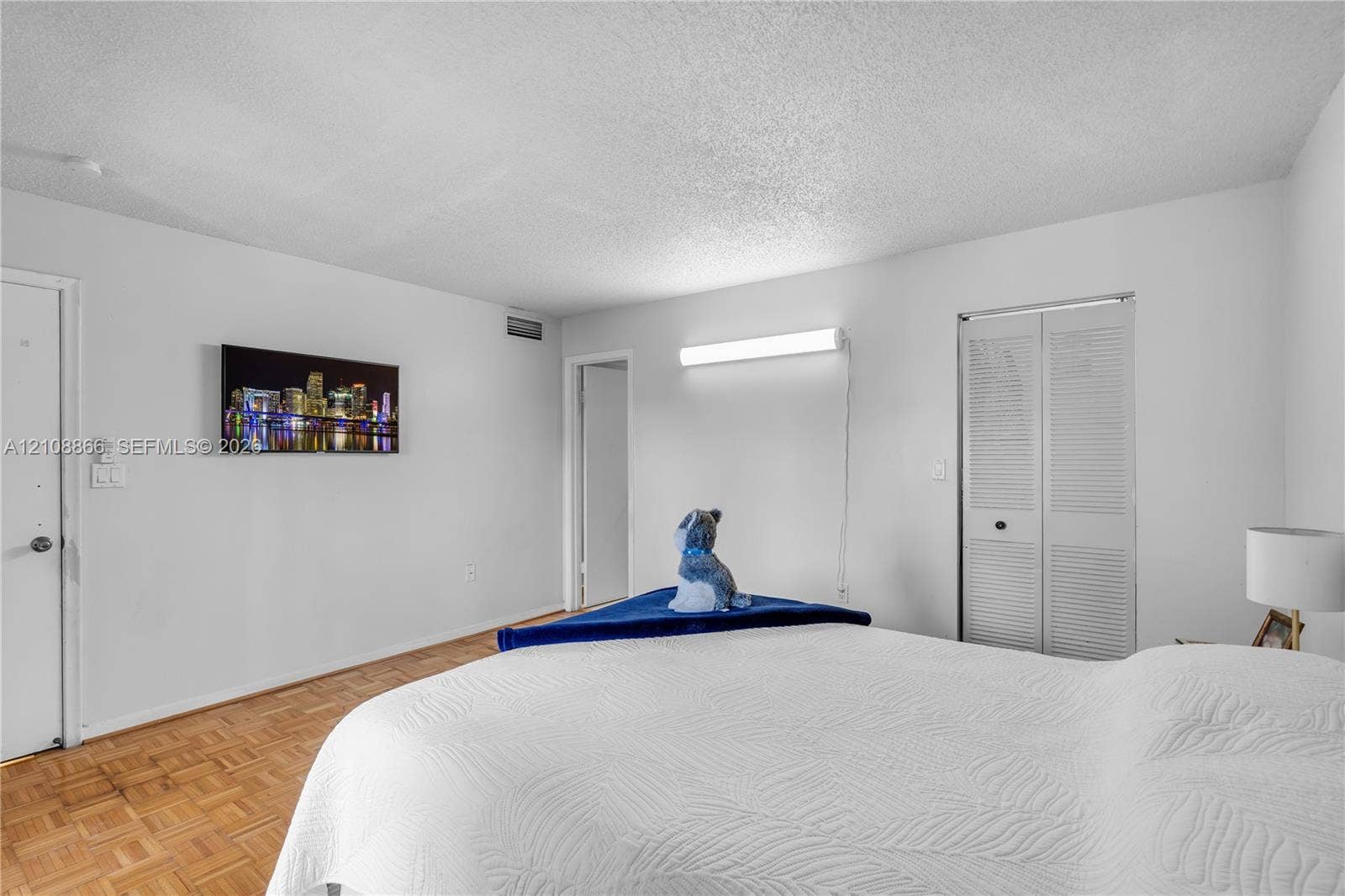 10859 NW 7th Street, #21-18, Miami, FL 33172 Parquet wood-finish flooring, white walls, and a closet with bifold louvered doors