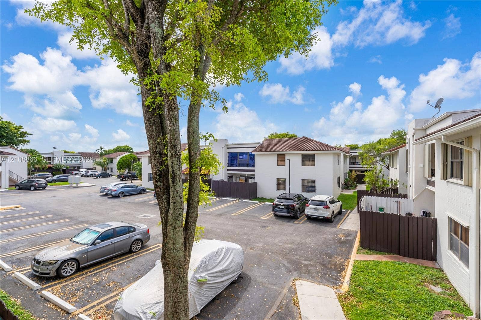 10859 NW 7th Street, #21-18, Miami, FL 33172 Exterior parking area with marked stalls, concrete wheel stops, and mature landscaping