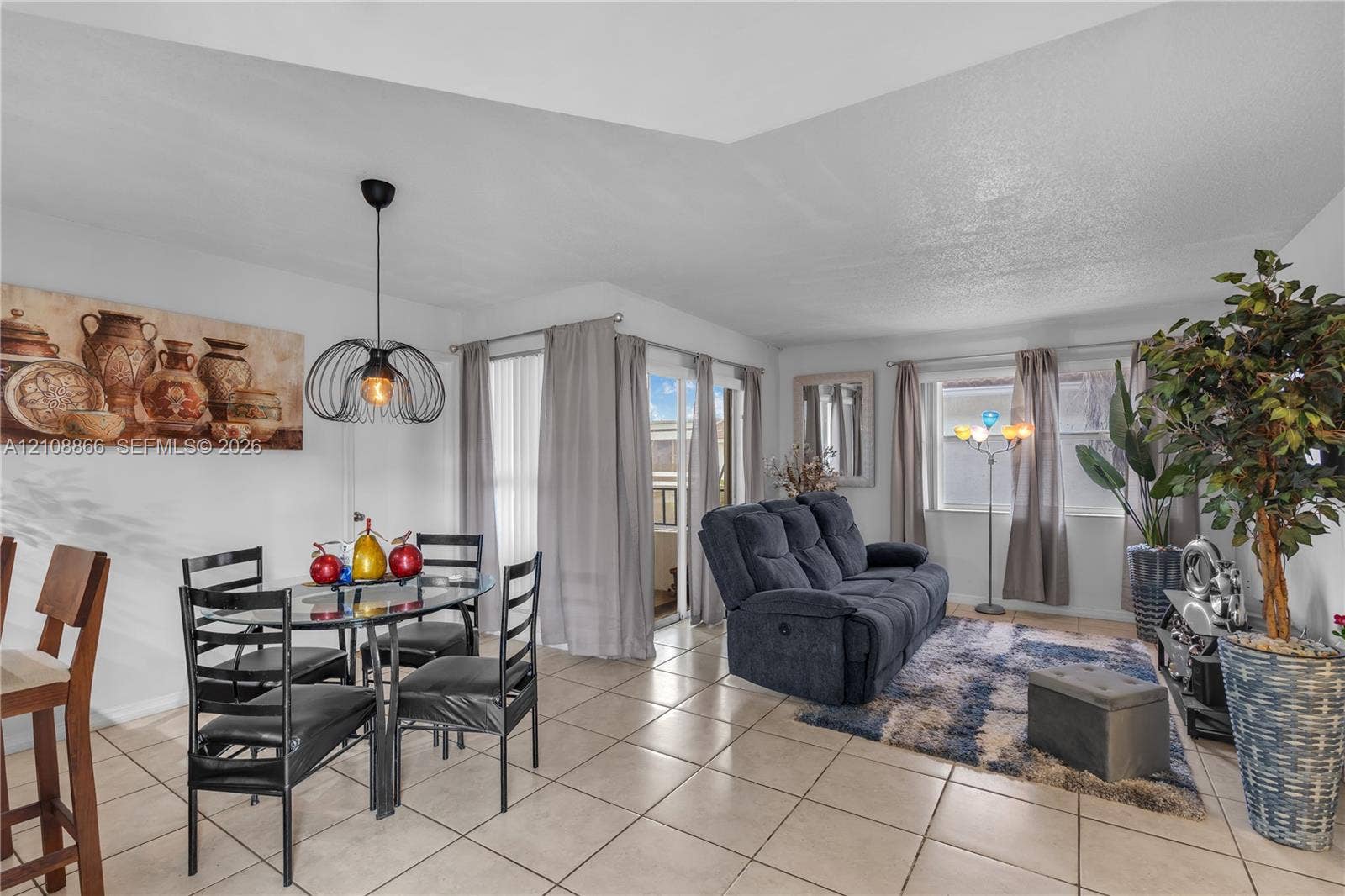 10859 NW 7th Street, #21-18, Miami, FL 33172 Open-concept space featuring neutral ceramic tile flooring, tray ceilings, and an industrial-style metal pendant light fixture